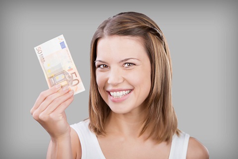 eine Frau mit langen Haaren hält eine 50 EUR Schein lachend in die Kamera