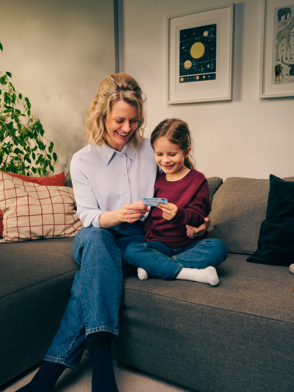 eine Mutter sitzt auf dem Sofa und liest mit ihrer Tochter ein Buch