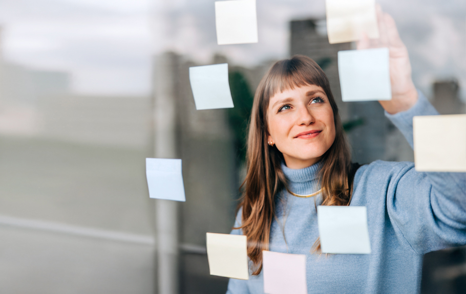 eine Frau steht am Fenster, an dem viele Post-It befestigt sind