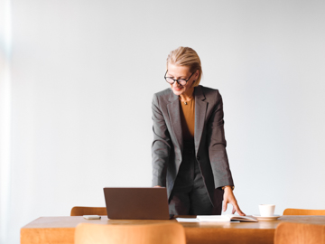 weibliche Person im Unternehmer-Outfit steht an einem Schreibtisch