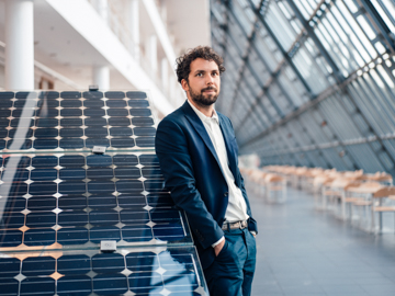 Mann im Anzug steht an einem Solarmodul
