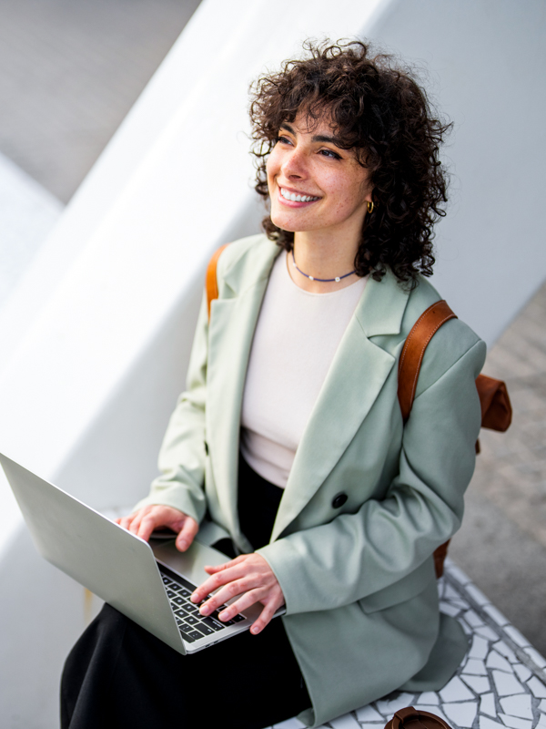 eine Frau sitzt lächelnd am Laptop